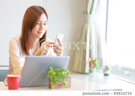 一個女人笑著操作智能手機 69910254