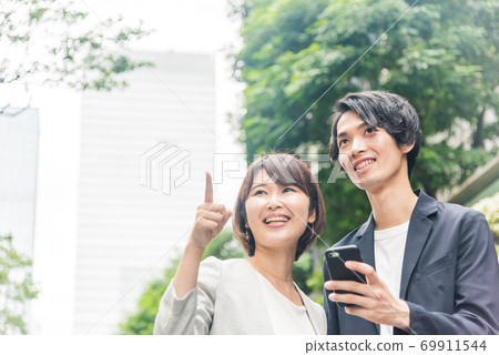 Men and women talking while looking at smartphones in the office district 69911544