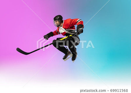 Male hockey player with the stick on ice court and neon colored gradient background. Sportsman wearing equipment, helmet practicing. 69911568