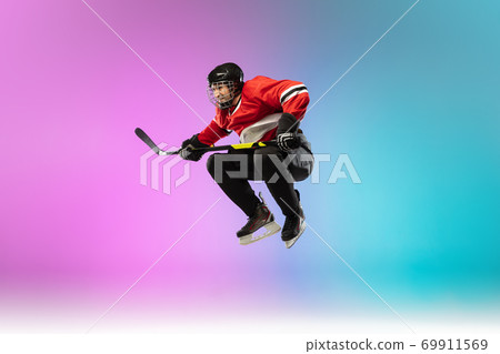 Male hockey player with the stick on ice court and neon colored gradient background. Sportsman wearing equipment, helmet practicing. Male hockey player with the stick on ice court and neon colored gradient background. Sportsman wearing equipment, helmet practicing. 69911569