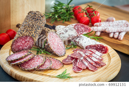 Assorted sliced italian salami on wooden plate Assorted sliced italian salami on wooden plate 69912131