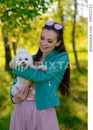 Young woman with dog. Puppy white dog is running with it's owner. Concept about friendship, animal Young woman with dog. Puppy white dog is running with it's owner. Concept about friendship, animal 69912711