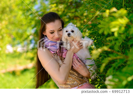Young woman with dog. Puppy white dog is running with it's owner. Concept about friendship, animal Young woman with dog. Puppy white dog is running with it's owner. Concept about friendship, animal 69912713