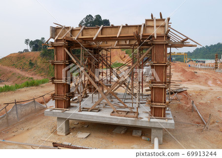 KUALA LUMPUR, MALAYSIA -SEPTEMBER 19, 2020: Column timber formwork and reinforcement bar at the construction site. Installed by construction workers. The structure supported by temporary wood support. KUALA LUMPUR, MALAYSIA -SEPTEMBER 19, 2020: Column timber formwork and reinforcement bar at the construction site. Installed by construction workers. The structure supported by temporary wood support. 69913244