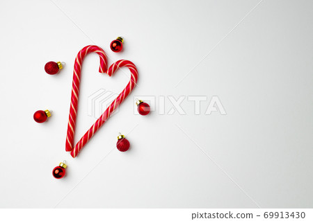 Candy canes and Christmas baubles on white background Candy canes and Christmas baubles on white background 69913430