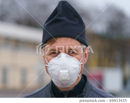 Man wearing protective mask outdoors. Coronavirus pandemic time. Man wearing protective mask outdoors. Coronavirus pandemic time. 69913435