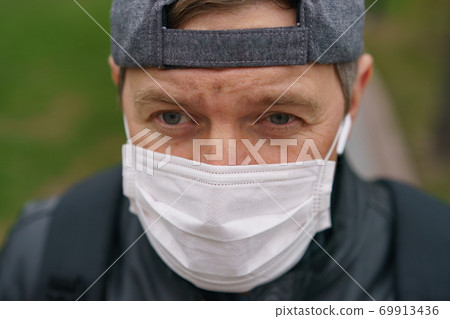 Man wearing protective mask outdoors. Coronavirus pandemic time. Man wearing protective mask outdoors. Coronavirus pandemic time. 69913436