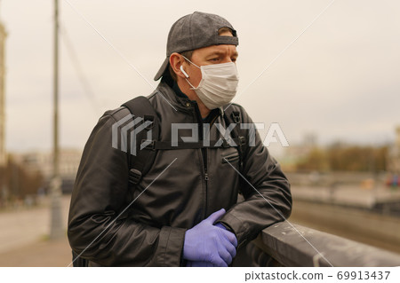 Man wearing protective mask outdoors. Coronavirus pandemic time. Man wearing protective mask outdoors. Coronavirus pandemic time. 69913437