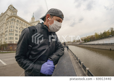 Man wearing protective mask outdoors. Coronavirus pandemic time. Man wearing protective mask outdoors. Coronavirus pandemic time. 69913440