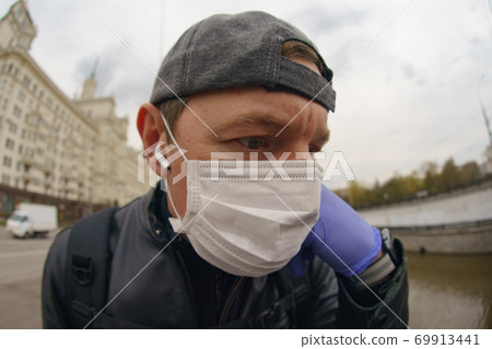 Man wearing protective mask outdoors. Coronavirus pandemic time. Man wearing protective mask outdoors. Coronavirus pandemic time. 69913441