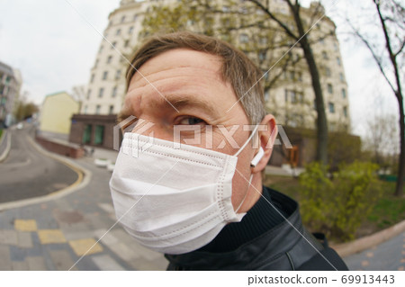 Man wearing protective mask outdoors. Coronavirus pandemic time. 69913443