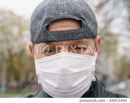 Man wearing protective mask outdoors. Coronavirus pandemic time. Man wearing protective mask outdoors. Coronavirus pandemic time. 69913444