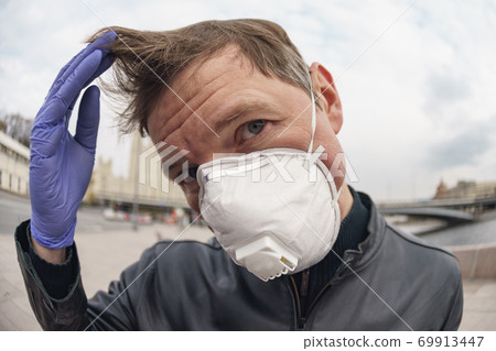 Man wearing protective mask outdoors. Coronavirus pandemic time. Man wearing protective mask outdoors. Coronavirus pandemic time. 69913447
