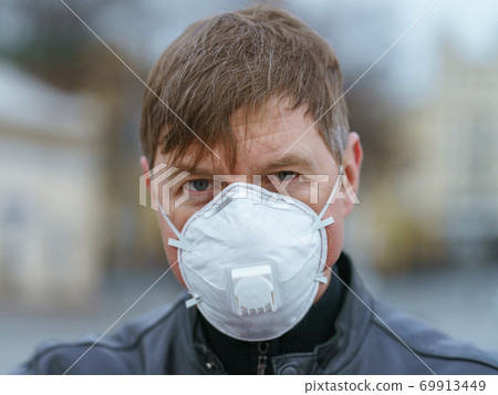 Man wearing protective mask outdoors. Coronavirus pandemic time. Man wearing protective mask outdoors. Coronavirus pandemic time. 69913449