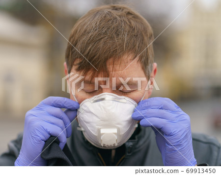 Man wearing protective mask outdoors. Coronavirus pandemic time. 69913450