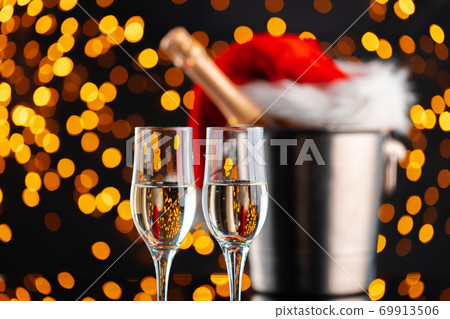 Champagne and Santa Claus hat on blurred garland background 69913506