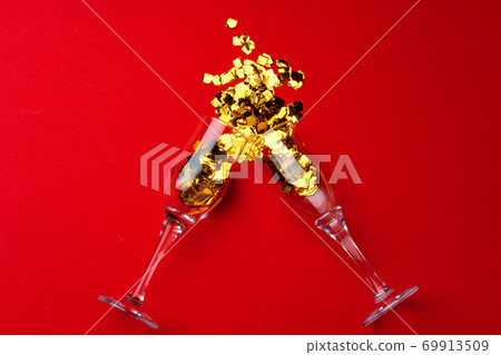 Champagne glass with glitter confetti on red background flat lay 69913509