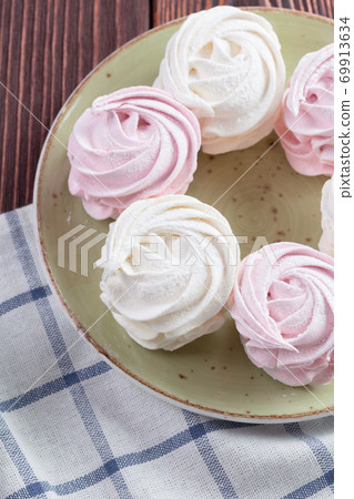 Pink and white meringue cookies on green plate Pink and white meringue cookies on green plate 69913634