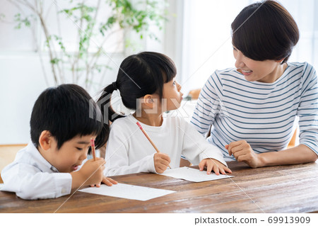 Brothers and mother doing homework in the living room. Brothers and mother doing homework in the living room. 69913909