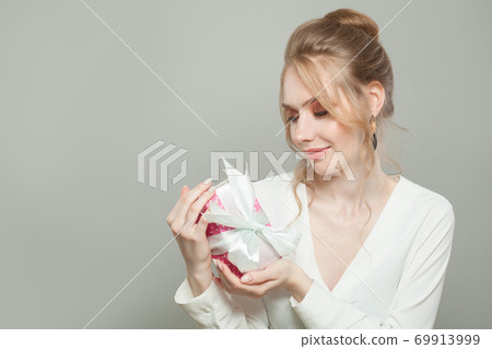 Attractive woman with gift on gray background 69913999