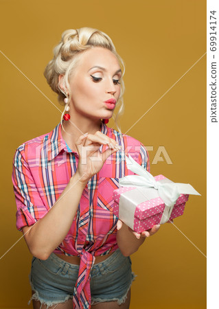 Pinup model woman with gift on yellow. Beautiful retro model portrait Pinup model woman with gift on yellow. Beautiful retro model portrait 69914174