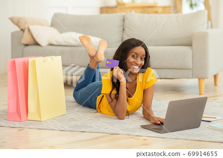 Online shopping and delivery. Positive black woman with credit card and laptop ordering goods on web at home 69914655
