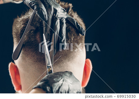 Cropped shot of barber cutting hair of customer with scissors Cropped shot of barber cutting hair of customer with scissors 69915030