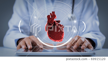 Doctor in coat using tablet with virtual heart hologram 69915120