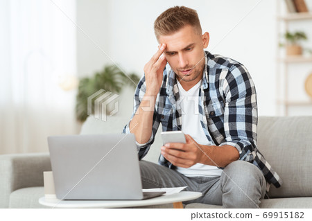 Sad adult man using smart phone at home 69915182