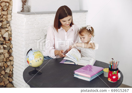 Tutor with litthe girl studying at home 69915267