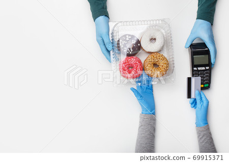 Sweets and cake set and modern payment. Client picks up container of donuts with bright glaze and pay by credit card at terminal 69915371