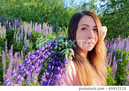Close-up portrait of caucasian young woman with long red hair, against the background of greenery in lupin`s field. Beautiful gathering flowers female. She is a successful florist. Close-up portrait of caucasian young woman with long red hair, against the background of greenery in lupin`s field. Beautiful gathering flowers female. She is a successful florist. 69915518
