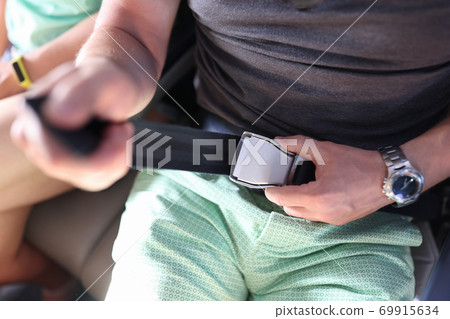 Man fastens his seat belt on an airplane. Man fastens his seat belt on an airplane. 69915634