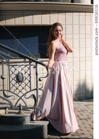 Beautiful young model posing to photographer. Woman with curly hair and makeup 69916316