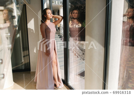 Elegant young woman stand by big window in luxury restaurant 69916318