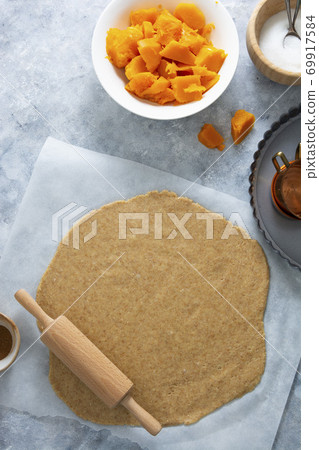Rolled out dough for pie, or tart crust with pumpkin, squash. Cooking autumn dessert. 69917584