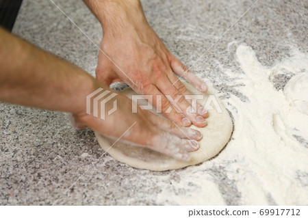 Making dough by male hands on table background. 69917712