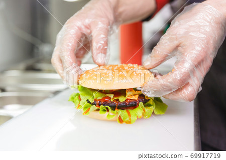 The chef's hands demonstrate the finished Burger. The chef's hands demonstrate the finished Burger. 69917719