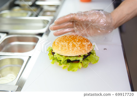 The chef's hands demonstrate the finished Burger. The chef's hands demonstrate the finished Burger. 69917720