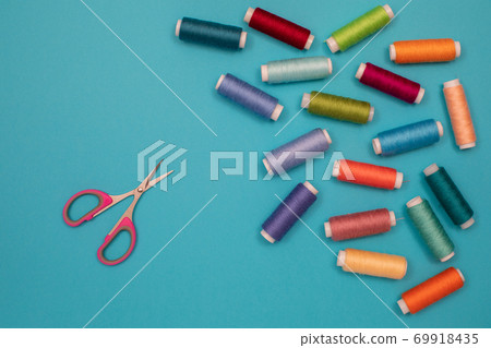 Multicolored cotton threads, spools, scissors, handmade sewing. Top view with copyspace, flat lay. Multicolored cotton threads, spools, scissors, handmade sewing. Top view with copyspace, flat lay. 69918435