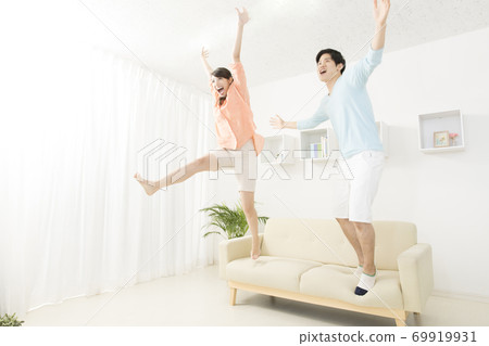 Couple jumping on the couch Couple jumping on the couch 69919931