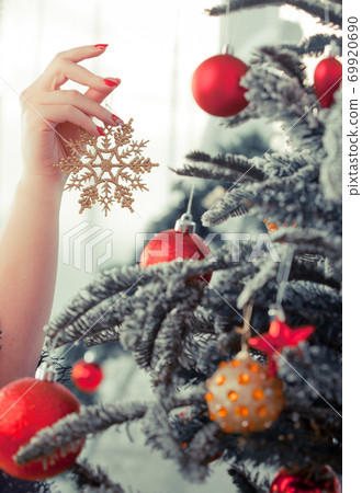 A woman's hand decorates a tree with snowflake toys A woman's hand decorates a tree with snowflake toys 69920690