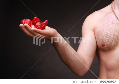 A handful of fresh red strawberry berries on a man's hand A handful of fresh red strawberry berries on a man's hand 69920692