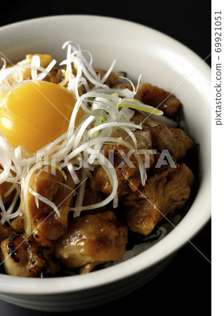 A bowl of white-haired green onions and egg yolk on top of a charcoal-grilled yakitori (black background) 69921051