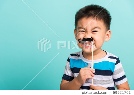Funny happy hipster kid holding black mustache 69921761