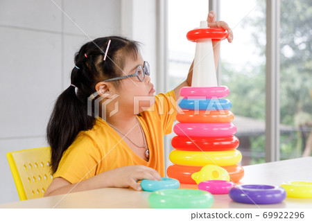 Girl with Down's syndrome play colorful toy at school. Concept disabled child learning in school. 69922296