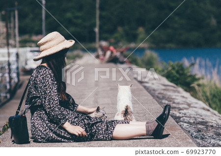 Woman in straw hat and cat on the island 69923770