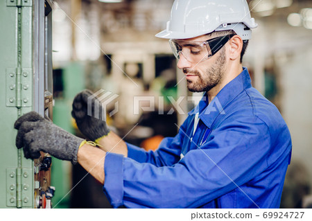 Hispanic latin labor worker hard working with safety glasses and helmet in factory 69924727