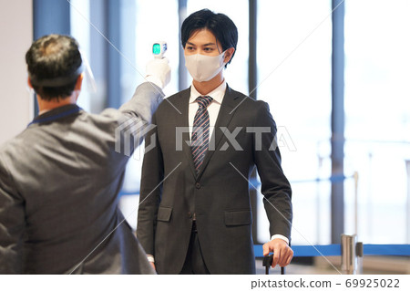 Men taking body temperature measurements with a non-contact thermometer Men taking body temperature measurements with a non-contact thermometer 69925022