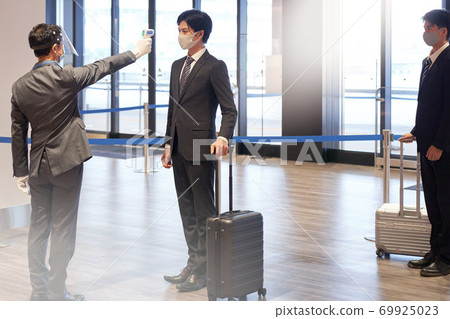 Men taking body temperature measurements with a non-contact thermometer Men taking body temperature measurements with a non-contact thermometer 69925023